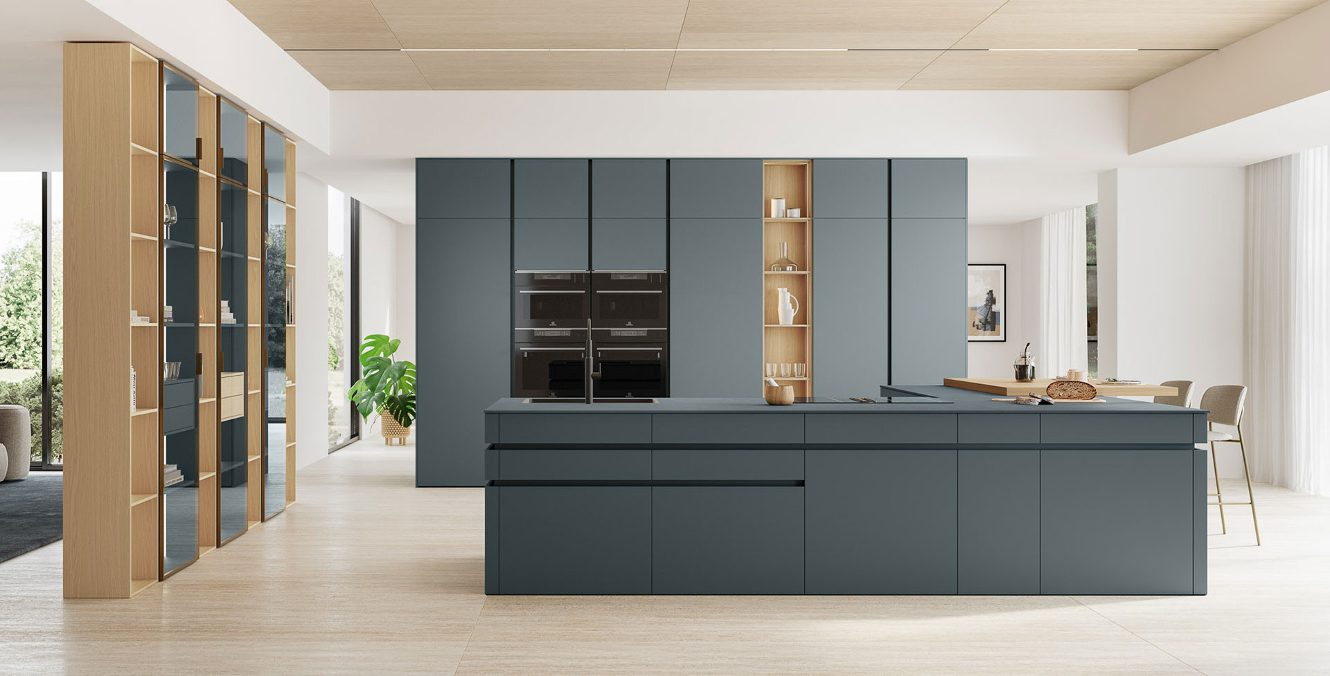 Cucina blu grigio opaco con isola, colonne dotate di doppio forno a incasso, libreria in rovere e ante vetrate